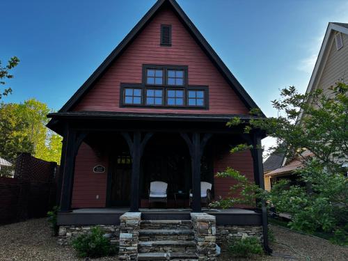 a red house with two white chairs on the porch at Quiet Getaway at Wayward Cottage in Pisgah
