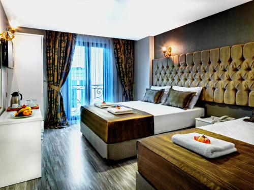 イスタンブールにあるGrand Pamir Hotelのベッド2台と大きな窓が備わるホテルルームです。