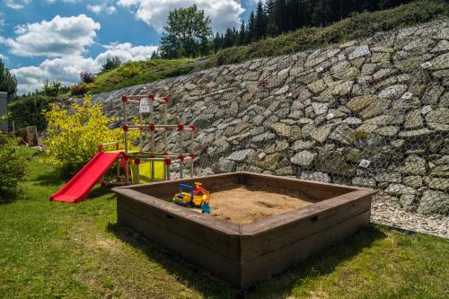 a sandbox with a toy in it next to a playground at Prázdninový dům - Apartmány Vltavice in Horní Vltavice