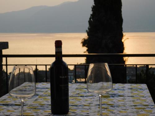a bottle of wine sitting on a table with two wine glasses at Villa Maria Lake View,7 minuti a piedi dal centro, parcheggio privato in Torri del Benaco