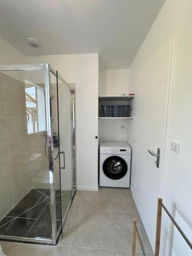 une salle de bain avec une machine à laver et un lave-linge dans l'établissement les Gîtes de Sophie 85 gîte Coquelicot 2 personnes, à Saint-Gervais