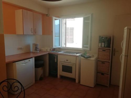 une petite cuisine avec un évier et une fenêtre dans l'établissement Appartement face au quai d'honneur, à Calvi