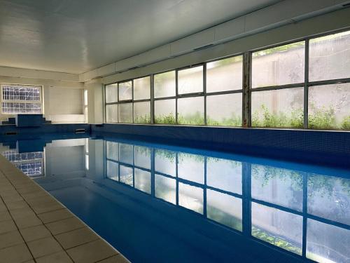 - une piscine avec fenêtres dans un bâtiment dans l'établissement 3 Pieces Convention Avec Piscine, à Paris