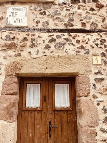 a stone building with a wooden door and two windows at ViLA VELLA 1 in Santa Pau