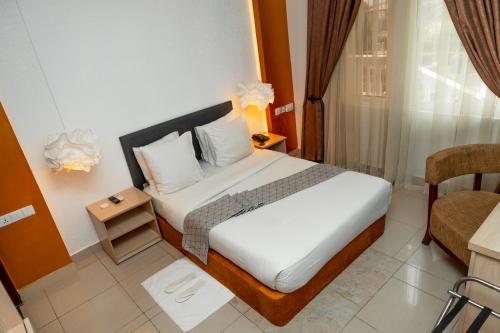 a hotel room with a bed and a chair at Amata n'Ubuki Boutique Hotel Ltd in Kigali