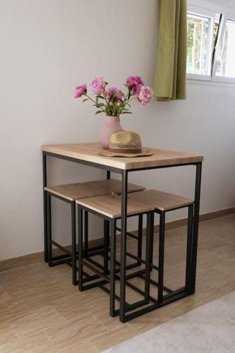 une table et un tabouret avec un vase avec des fleurs dessus dans l'établissement Studio frais & cosy Lyon-LDLC Arena Lyon - Eurexpo - LDLC Arena - Groupama Stadium - Eurexpo - 15mn Lyon, à Corbas