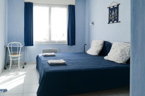 une chambre avec un lit bleu avec deux serviettes dessus dans l'établissement Appartement quartier des Présidents avec vue sur la baie des Sables d'Olonne - 4 personnes, à Les Sables-dʼOlonne