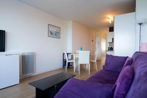 un salon avec un canapé violet et une table dans l'établissement Appartement quartier des Présidents avec vue sur la baie des Sables d'Olonne - 4 personnes, à Les Sables-dʼOlonne
