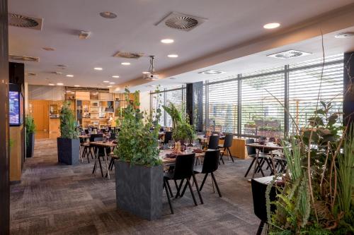 a restaurant with tables and chairs and potted plants at Hotel Vista in Brno