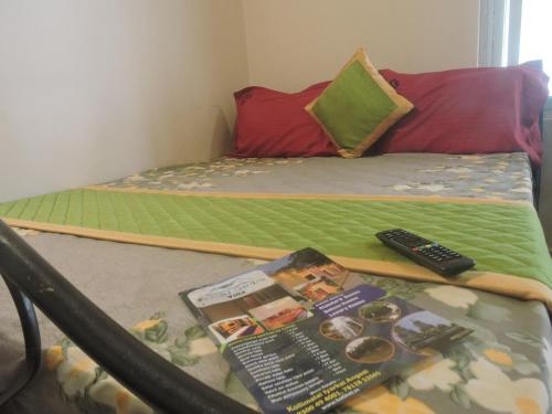 a bed with a book and a remote control on it at Kanna Garden by Bodhi Bungalows in Kolli Hills