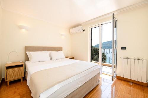 een witte slaapkamer met een groot bed en een groot raam bij Boka Apartment 1 in Herceg-Novi