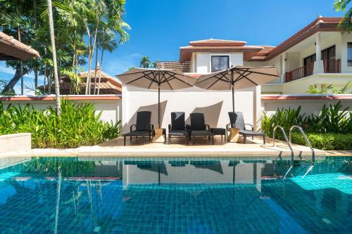a swimming pool with chairs and an umbrella next to a house at Angsana Villas Laguna-3 Bedroom Pool Villa in Phuket