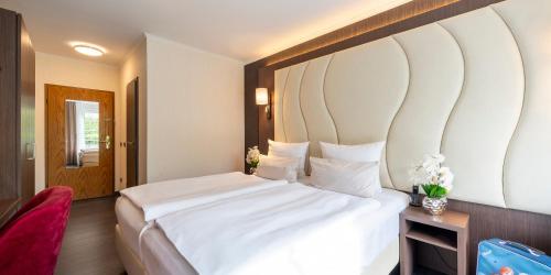 a bedroom with a large bed with a large headboard at Best Western Hotel Schmoeker-Hof in Norderstedt