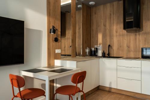 a kitchen with two orange chairs and a table at RentPlanet - Kępa Mieszczańska II in Wrocław