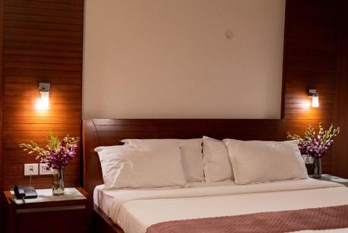 a bedroom with a large bed with white pillows at Sree Parijatha Grand in Bengaluru