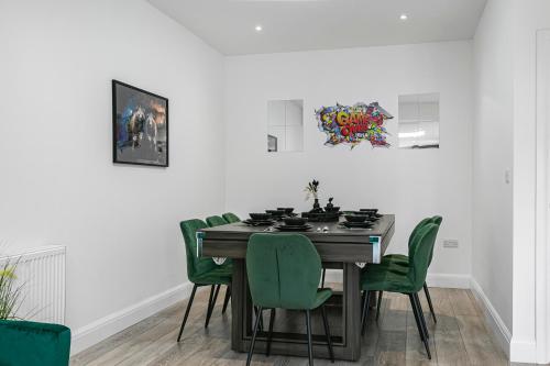 a dining room with a table and green chairs at Spacious Detached House with 7 Beds Includes Ping Pong and Pool Table Sleeps 14 Free Parking in Feltham
