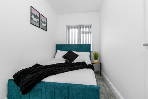 a bedroom with a bed with a blue headboard at Spacious Detached House with 7 Beds Includes Ping Pong and Pool Table Sleeps 14 Free Parking in Feltham