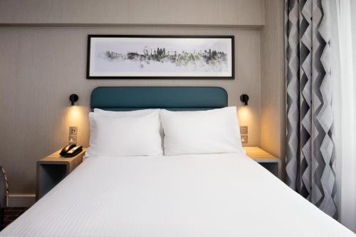a bedroom with a large bed with white pillows at City Sleeper at Royal National Hotel in London