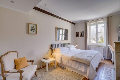 une chambre avec un grand lit et une chaise dans l'établissement Demeure de la Combe, à Saint-Émilion