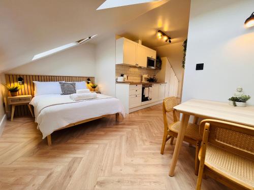 a bedroom with a bed and a table and a kitchen at The Nook Londons Swanky Studio with FREE Parking in London