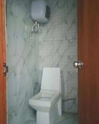 a bathroom with a toilet and a marble wall at ATS Grand Casa 02 in Greater Noida