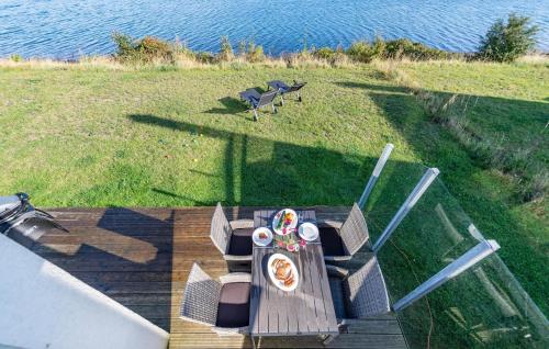 a table and chairs on a deck next to the water at Sommer Kajüte in Olpenitz