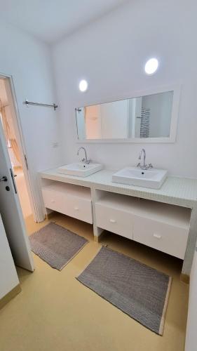 a bathroom with two sinks and a large mirror at Surf House Casa Vehla in Sal Rei