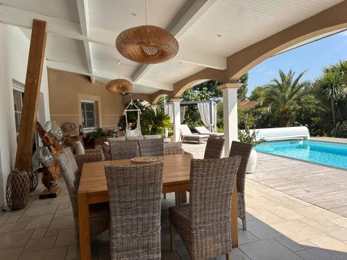 une salle à manger avec une table et des chaises et une piscine dans l'établissement Chambre d hôte village aéronautique Biscarrosse, à Biscarrosse