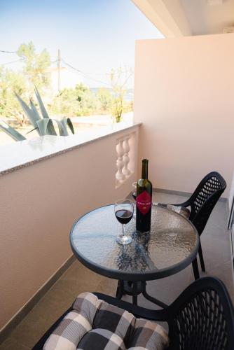 a table with a bottle of wine and a glass at Apartmani Natalija 4 Stars in Mrljane