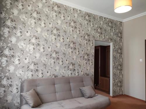a living room with a couch in front of a floral wall at Hotel Restauracja Rondo in Kutno