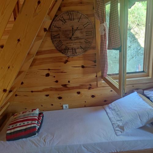 a clock on the wall of a room with a bed at Seoski Turizam Feniks apartman Davidovi Psalmi in Kosjerić