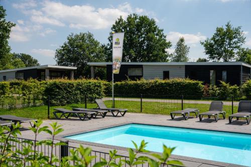 a swimming pool with patio furniture and a building at Vakantiepark Buitenplaats Holten in Rijssen