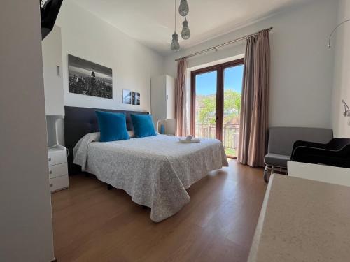 a bedroom with a bed with blue pillows and a window at Balcones de Bentomiz in Vélez-Málaga