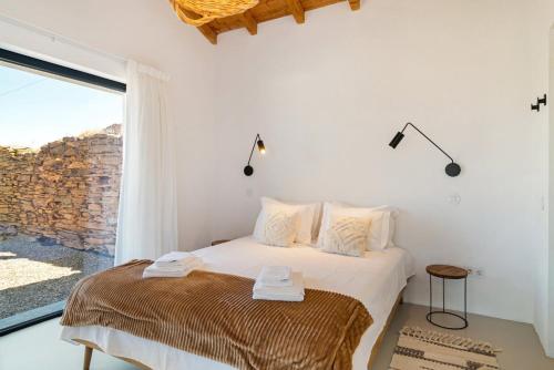 Un dormitorio blanco con una cama y una ventana grande. en Monte Muro Country House, en Monsaraz