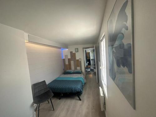 une chambre avec un lit et une chaise dans une pièce dans l'établissement F2 centre-ville tout confort 4 personnes, à Beaumont-sur-Oise