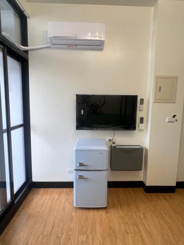 a room with a refrigerator and a tv on a wall at Chaonima B&B 潮尼馬民宿-屏東縣民宿編號第1458號 in Chaozhou