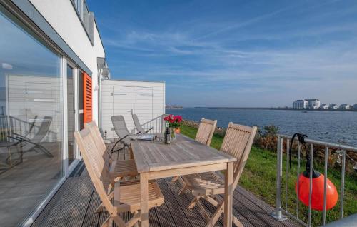 a wooden table and chairs on a deck with the water at B-Lodge in Olpenitz