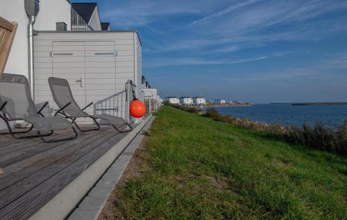 a deck with two chairs and a building and the water at B-Lodge in Olpenitz