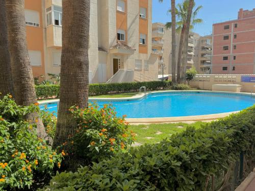 a swimming pool in front of a building at .Apartamento 1a linea de playa + piscina + parking DAIMUS in Daimuz