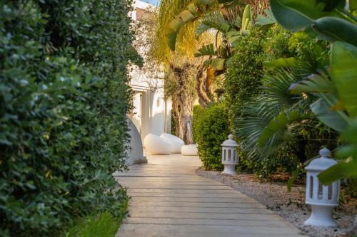 a walkway through a garden with trees and plants at Hotel Vecchia Marina in Àrbatax
