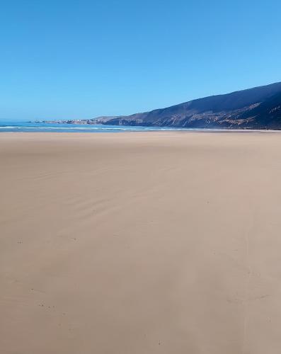 an empty beach with the ocean in the background at Tildi surf house in Imsouane