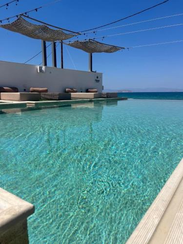 a swimming pool with clear blue water and umbrellas at NOIMA Casa Unico in Megalochori