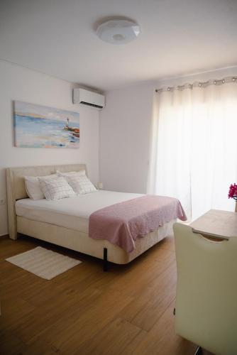 a white bedroom with a bed and a window at Apartmani Natalija 4 Stars in Mrljane
