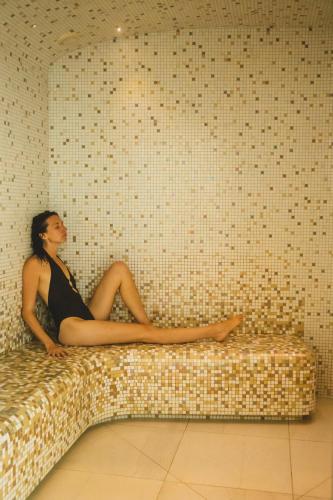 a woman in a black dress sitting on a couch at Miramar La Cigale Hotel Thalasso & Spa in Arzon
