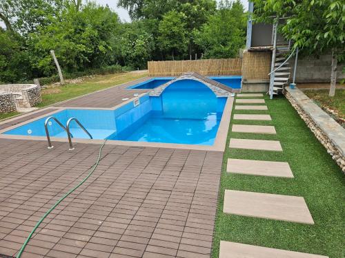 ein Swimmingpool mit gefliester Terrasse und Rasen in der Unterkunft Auto kamp Hacienda Kolenda in Mostar