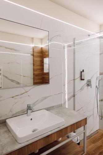 a white bathroom with a sink and a mirror at Jezioranka Apartamenty in Ostrzyce