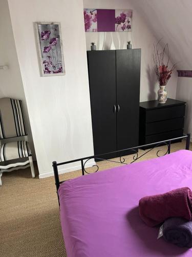 a bedroom with a purple bed and a black cabinet at Chambres d'hôte du Domaine de la Reine Blanche in Criquetot-sur-Longueville