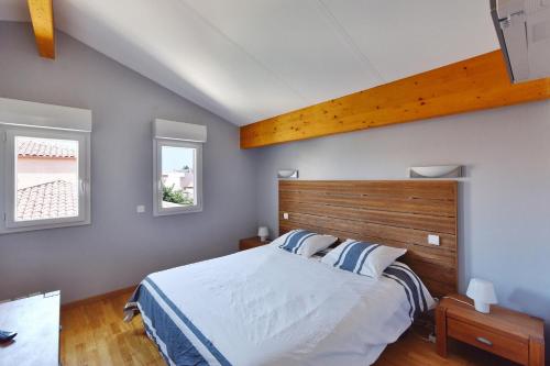 une chambre avec un grand lit avec une tête de lit en bois dans l'établissement Villa de l'Art, à Saint Cyprien Plage