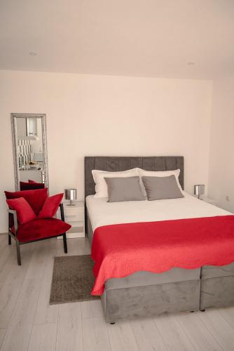 a bedroom with a large bed and a red chair at Apartmani Natalija 4 Stars in Mrljane