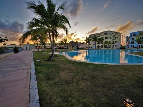 a swimming pool with a palm tree and a building at Propiedad Fishing Lodge in Punta Cana
